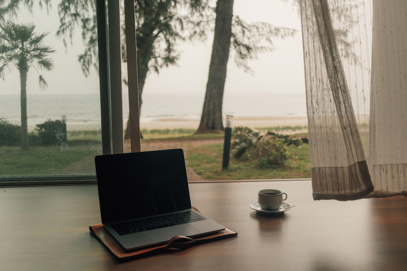 laptop and hot coffee near a beach